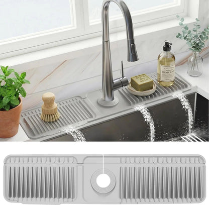 Gray silicone faucet splash guard mat installed behind kitchen sink with auto-drain channels